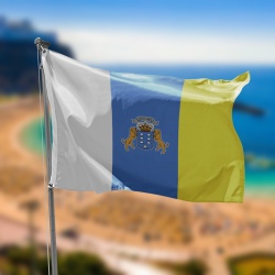 Bandera de canarias blanca azul y amarilla con el escudo de canarias en el centro sobre la playa de las teresitas